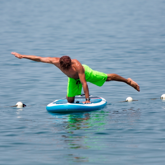 Man doing yoga on stand up paddle board