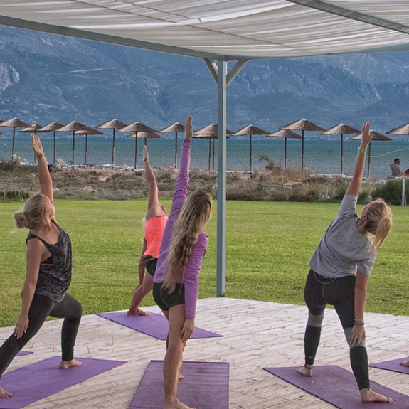 group of people doing yoga by the sea