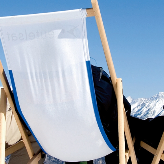 people relaxing on deck chairs soaking up the sun on a ski holiday