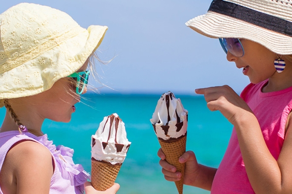 Two young girls eating ice cream on a beach in Italy
