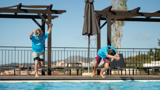 Kids jumping into a swimming pool