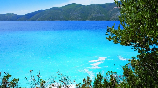 A clear body of water with hills in the background