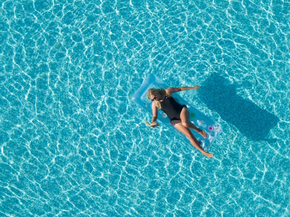 woman reading book while sunbathing in pool