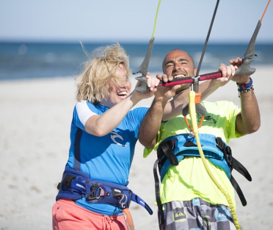 Two people on a beach engaged in kite surfing or kite flying training. 