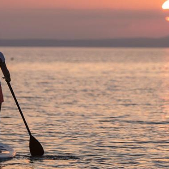 2 people stand up paddle boarding at sunset