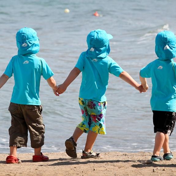 group of toddlers holdimg hands and walking along the beach