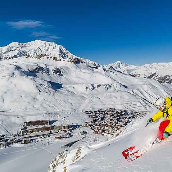 Person Skiing high above village in valley below 