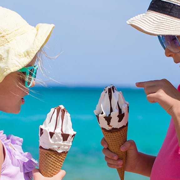 Two young girls eating ice cream on a beach in Italy