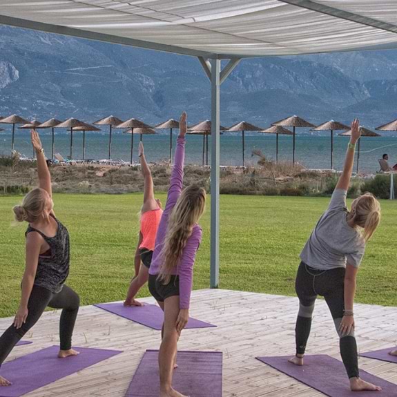 group of people doing yoga by the sea