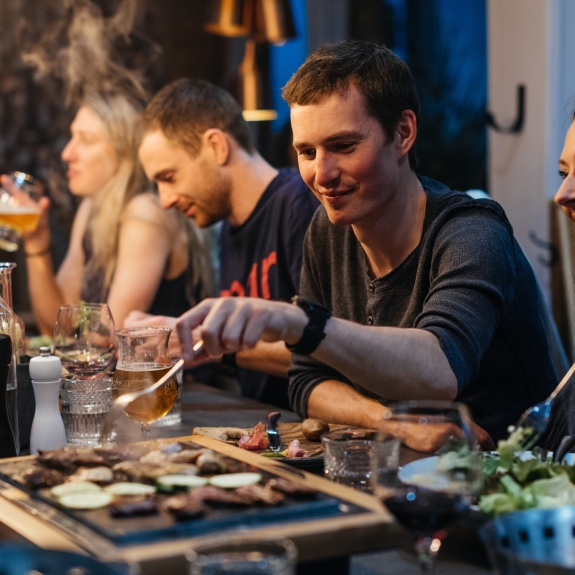 Group of people eating dinner around the table in a ski chalet