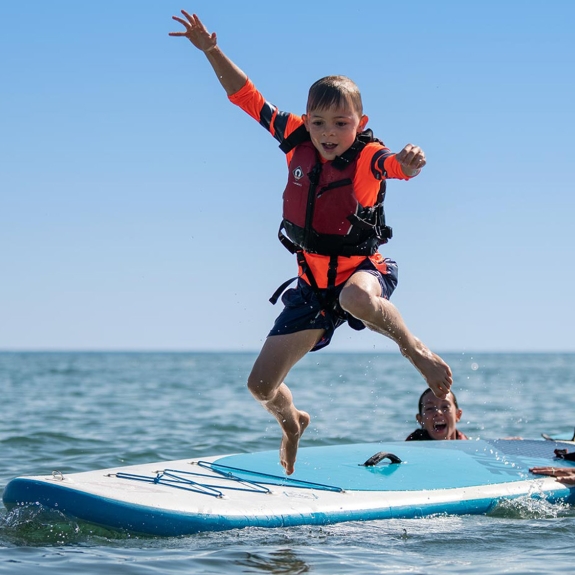 boy jumping from a paddle board
