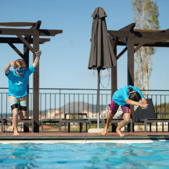 Kids jumping into a swimming pool