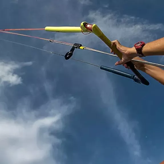 A woman dressed in orange kite surfs across the sea