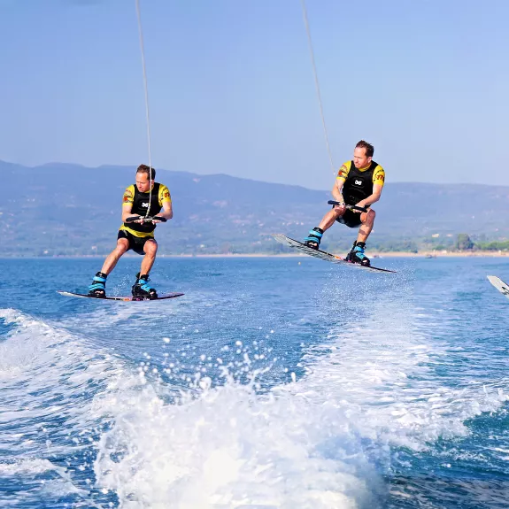 The image shows a sequence of a person wakeboarding captured at different stages of a jump over water.