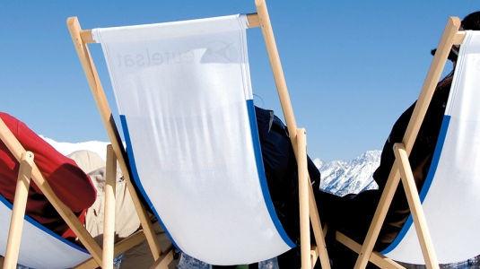 people relaxing on deck chairs soaking up the sun on a ski holiday