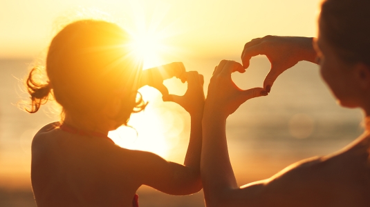 Woman and child on beach at sunset