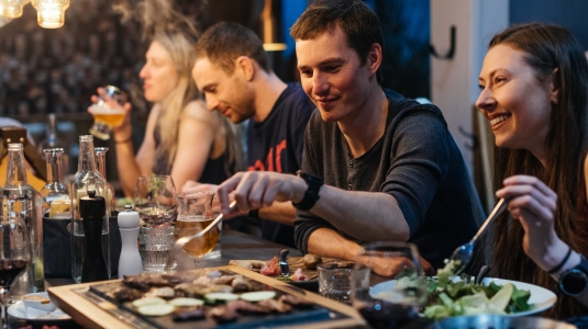 Group of people eating dinner around the table in a ski chalet