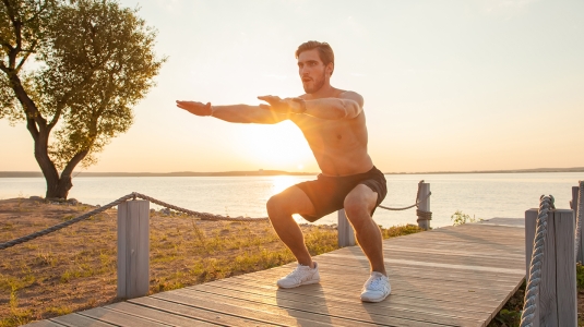 person doing squats on the beach