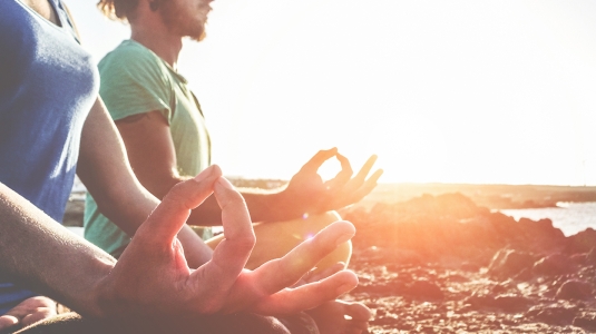 people meditating on the beach at sunset