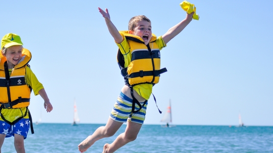 children in kids club jumping off a stand up paddle board