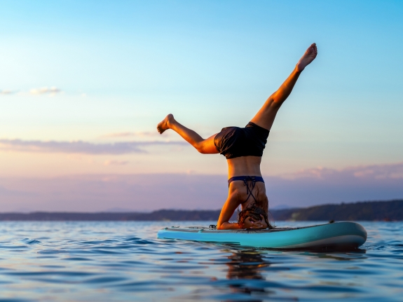 WOMAN DOING PADDLE BOARD YOGA