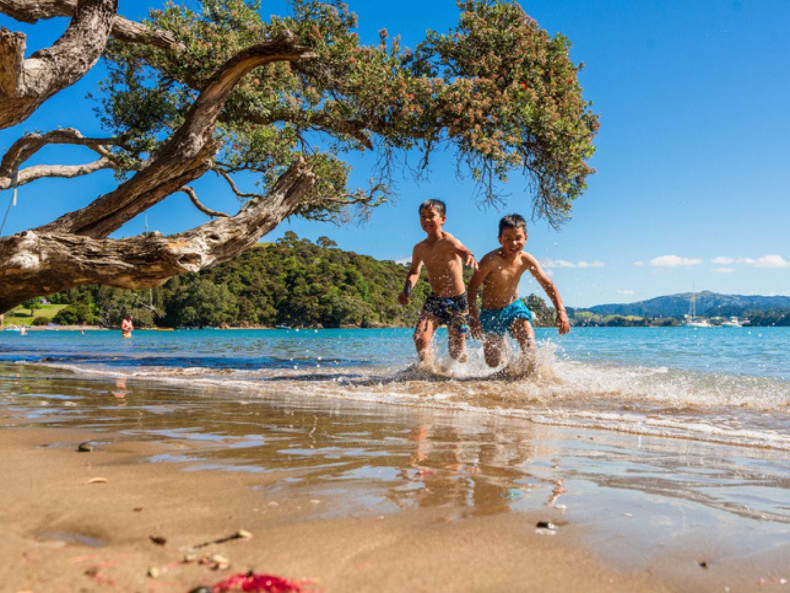 To glade, legende maori-børn på smuk strand i New Zealand