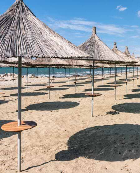 Parasoller på sandstrand i Golem, Albanien Parasoller på sandstrand i Golem, Albanien