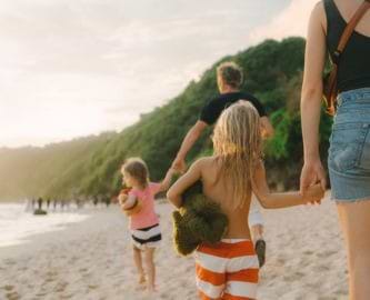Familie med to voksne og to børn går hånd i hånd på balinesisk strand