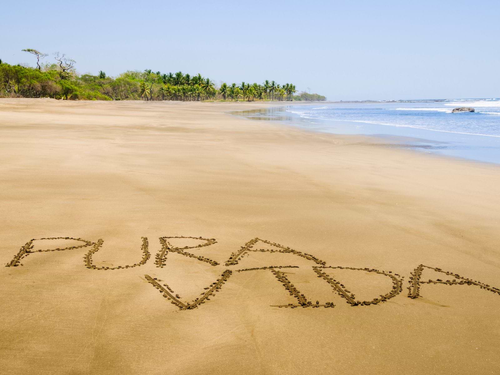 Pura Vida skrevet i sandet på eksotisk strand i Costa Rica Pura Vida skrevet i sandet på eksotisk strand i Costa Rica