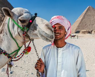 Smilende beduin foran pyramide i Giza, Egypten