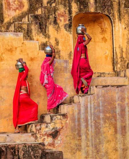 Tre indiske kvinder i farvestrålende klædedragter på trapper i Jaipur, Indien Tre indiske kvinder i farvestrålende klædedragter på trapper i Jaipur, Indien