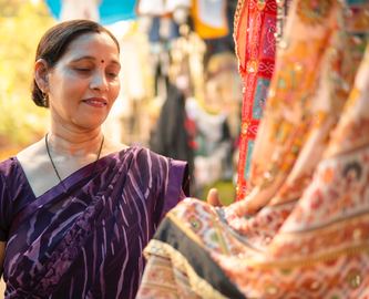 Indisk kvinde kigger på smukke tekstiler på marked i Indien