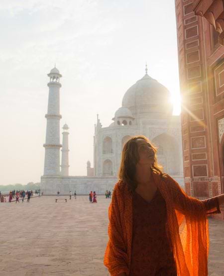 Kvinde foran Taj Mahal med lav sol, Indien