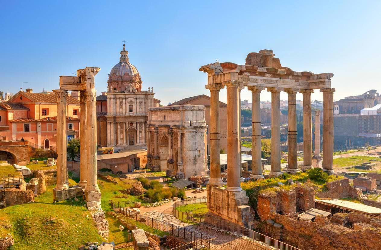 Romerske ruiner i Forum Romanum med marmorsøjler i forgrunden og kirken Santi Luca e Martina i sollys i hjertet af Rom, Italien.