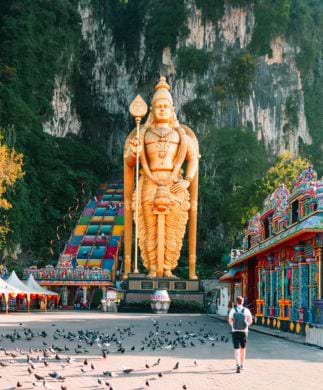 Mand og duer foran fatu Caves med den farvestålende trappe og store hindu-statue, Malaysia