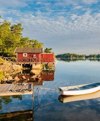 Rød træhutte og robåd i skærgården i Sverige
