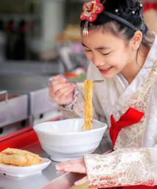 Koreansk kvinde i traditionel klædedragt spiser street food, Sydkorea Koreansk kvinde i traditionel klædedragt spiser street food, Sydkorea