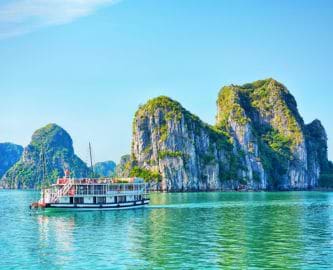 Båd sejler blandt smukke kalkstensklipper i Ha Long-bugten i Vietnam