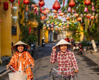 To cyklister i Vietnamesisk gade i Hoi An med lanterner