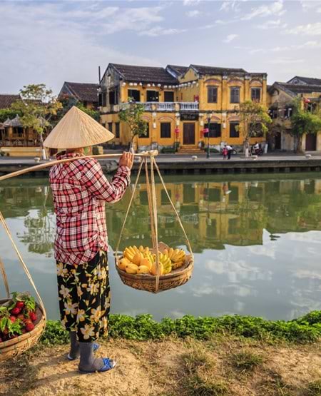 Vietnamesisk kvinde som sælger grøntsager og frugt i Hoi An