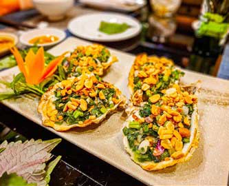 Vietnamesisk specialitet med friske, grillede østers med forårsløg og peanuts Vietnamesisk specialitet med friske, grillede østers med forårsløg og peanuts