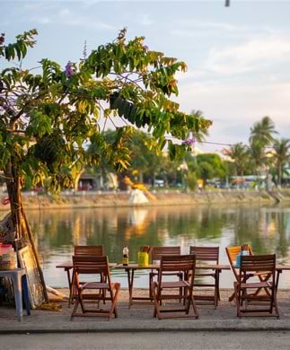 Hyggelig cafe i Hoi An i Vietnam med borde og stole foran floden. Hyggelig cafe i Hoi An i Vietnam med borde og stole foran floden.
