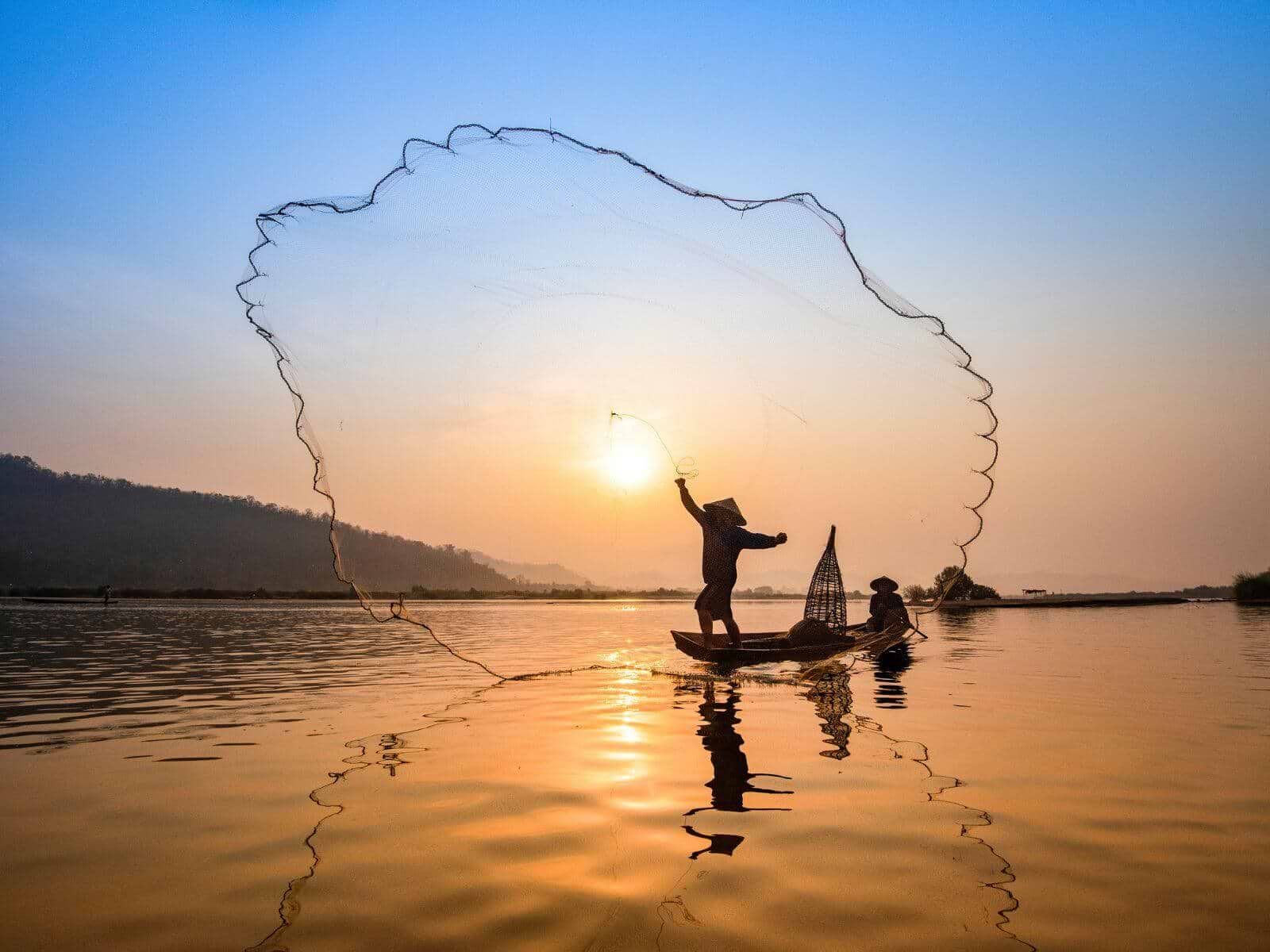 Vietnameser, der kaster fiskenet på Mekong-floden i solopgang, Vietnam