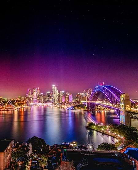 ydney Harbour Bridge og Sydneys skyline om aftenen. Credits: Australia Tourism.