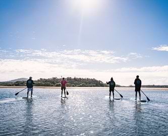 Familie på paddleboards ved stranden i Red Rock, Coffs Harbour