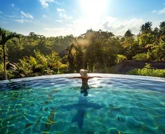 Kvinde i pool som nyder det frodige landskab på Bali Kvinde i pool som nyder det frodige landskab på Bali