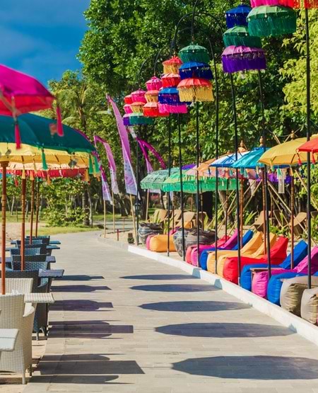 Farverige parasoller og liggestole ved strand i Nusa Dua, Bali