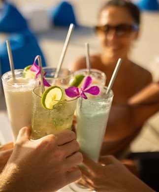 Venner som skåler i farverige drinks i Beach Club i Seminyak på Bali Venner som skåler i farverige drinks i Beach Club i Seminyak på Bali