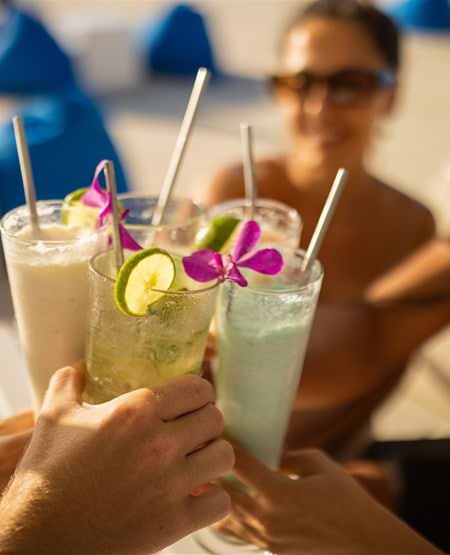 Venner som skåler i farverige drinks i Beach Club i Seminyak på Bali
