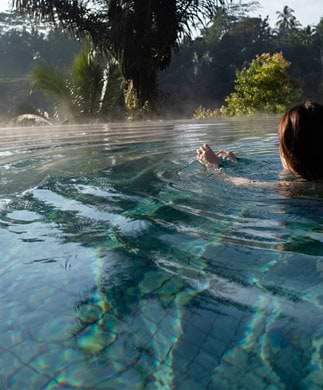 Poolafslapning på Bali Kvinde som nyder udsigten fra en pool på Bali